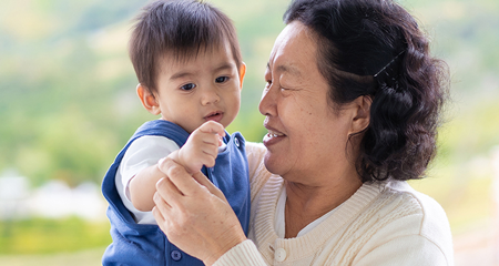 Happy and healthy asian grandmother is holding and playing with grandchild in the morning time on the background of nature, concept of multi generation living of asian family lifestyle.